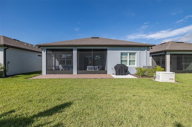 back of property featuring a sunroom, a shingled roof, a lawn, and stucco siding