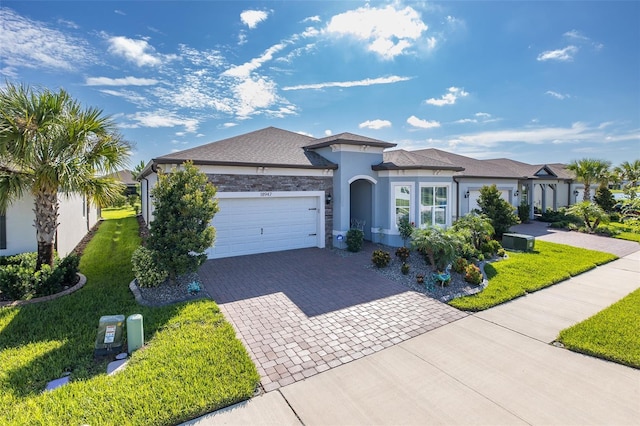 view of front facade featuring a front yard, decorative driveway, an attached garage, and stucco siding