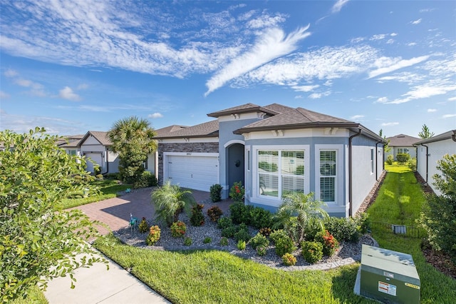 view of front of house with an attached garage, a front lawn, decorative driveway, and stucco siding