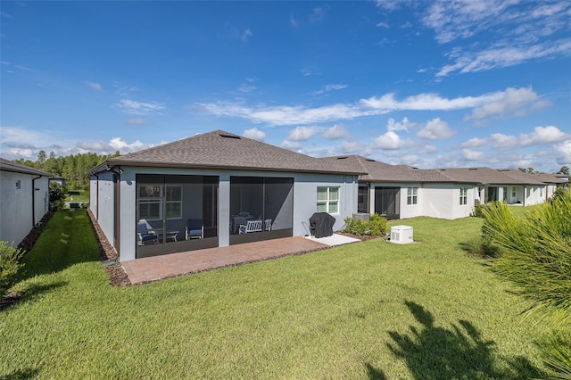 rear view of property featuring a patio, a lawn, a sunroom, and stucco siding