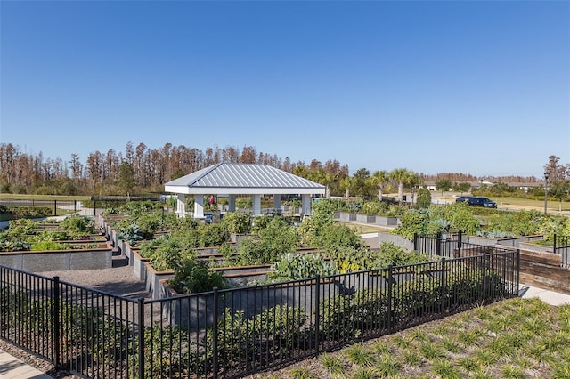 view of property's community featuring a gazebo, fence, and a garden