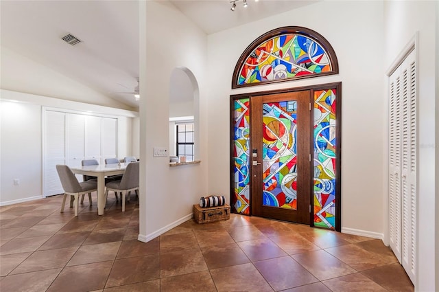 tiled foyer with lofted ceiling, a ceiling fan, visible vents, and baseboards