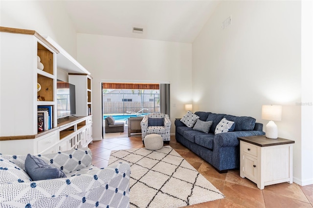 living area featuring light tile patterned floors, baseboards, visible vents, and high vaulted ceiling