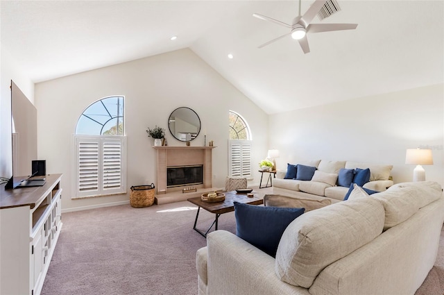 living room featuring ceiling fan, light colored carpet, a healthy amount of sunlight, and a glass covered fireplace