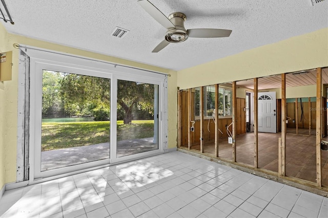empty room featuring a textured ceiling, ceiling fan, visible vents, and a healthy amount of sunlight