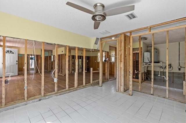 misc room with visible vents, tile patterned flooring, ceiling fan, a textured ceiling, and water heater