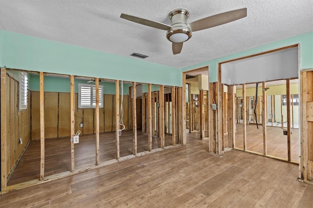 interior space featuring a textured ceiling, visible vents, and wood finished floors