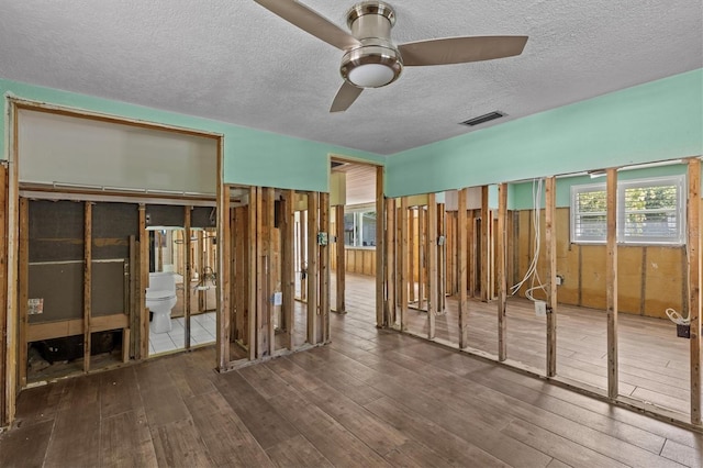 unfurnished bedroom featuring a textured ceiling, visible vents, multiple windows, and hardwood / wood-style floors