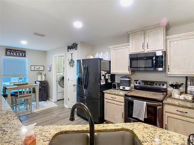 kitchen with light stone counters, a sink, washer / clothes dryer, stainless steel appliances, and light wood finished floors