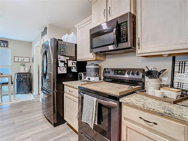 kitchen featuring light wood finished floors, stainless steel appliances, and light stone countertops