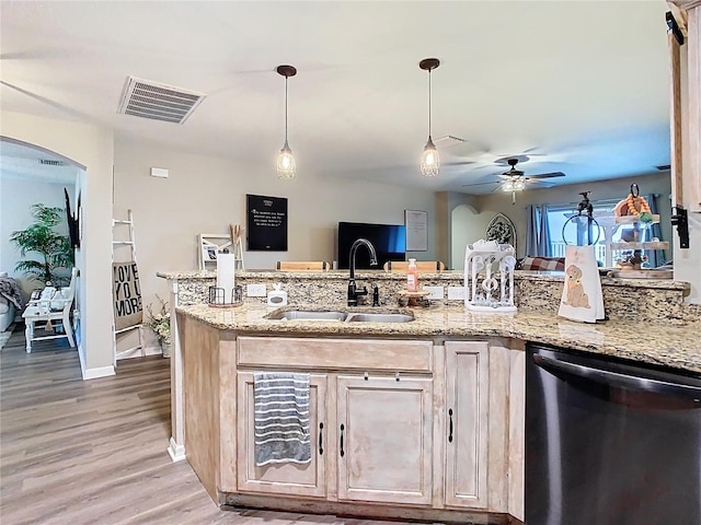 kitchen featuring visible vents, a sink, stainless steel dishwasher, arched walkways, and light stone countertops