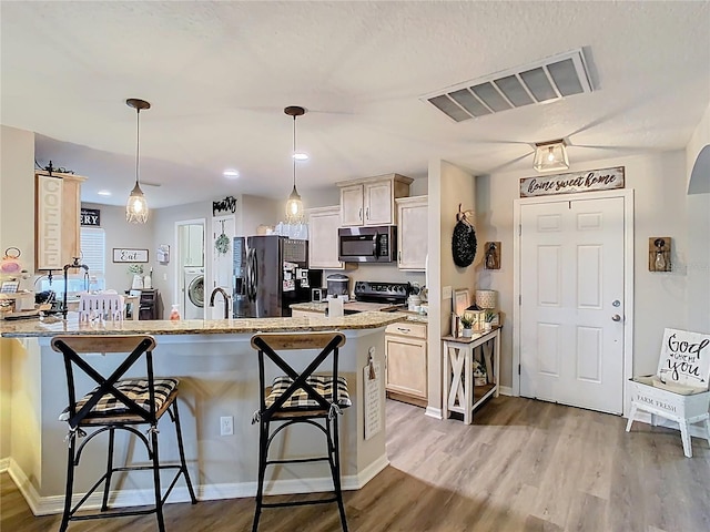 kitchen with visible vents, electric range, a kitchen bar, stainless steel microwave, and black refrigerator with ice dispenser