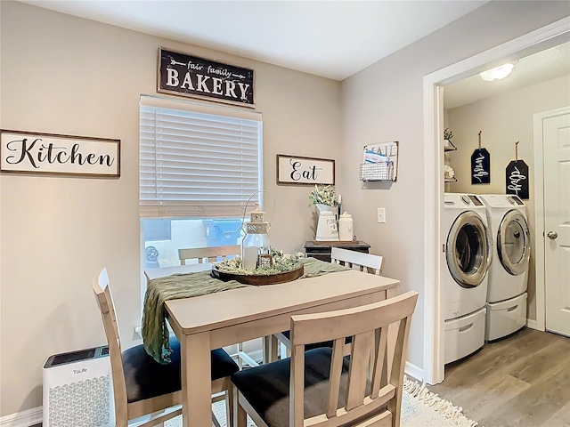 clothes washing area with baseboards, light wood finished floors, laundry area, and washing machine and clothes dryer