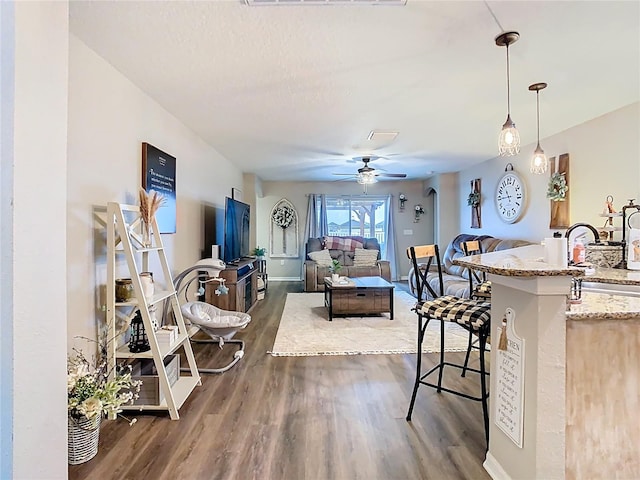 living area with visible vents, baseboards, a ceiling fan, and dark wood-style flooring