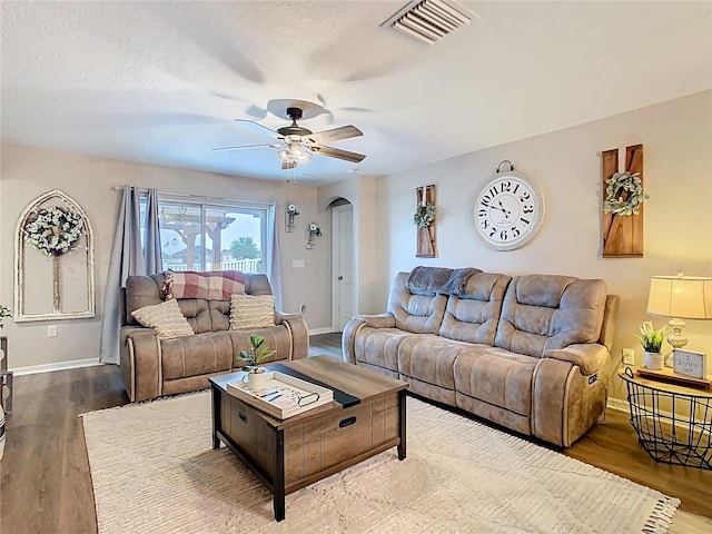 living room featuring a ceiling fan, wood finished floors, arched walkways, and visible vents