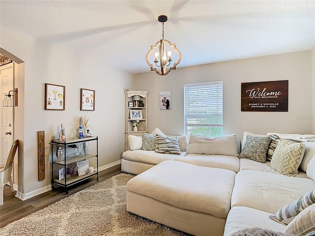 living room with a chandelier, baseboards, and wood finished floors