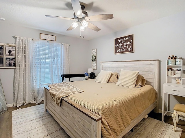 bedroom featuring ceiling fan, baseboards, and wood finished floors