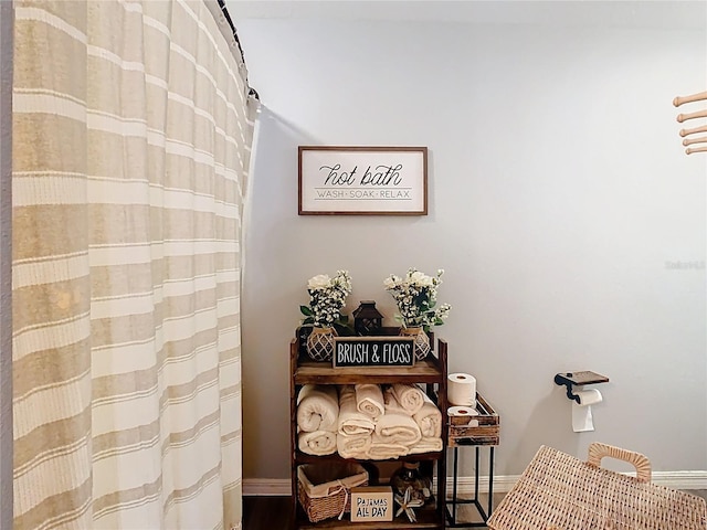 interior details featuring a shower with shower curtain and baseboards