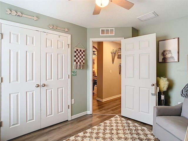 interior space featuring ceiling fan, wood finished floors, visible vents, and baseboards