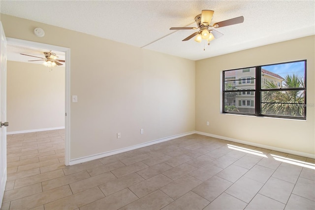 empty room featuring light tile patterned floors, a ceiling fan, baseboards, and a textured ceiling