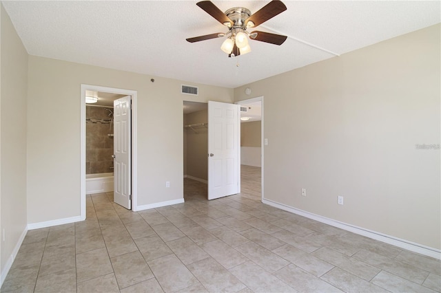 unfurnished bedroom featuring visible vents, a walk in closet, a closet, baseboards, and ceiling fan