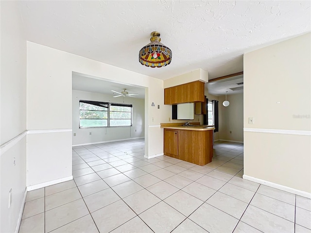 kitchen featuring light tile patterned floors, open floor plan, brown cabinetry, and light countertops