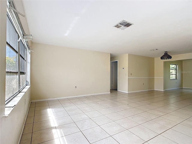 spare room featuring light tile patterned floors, visible vents, and baseboards