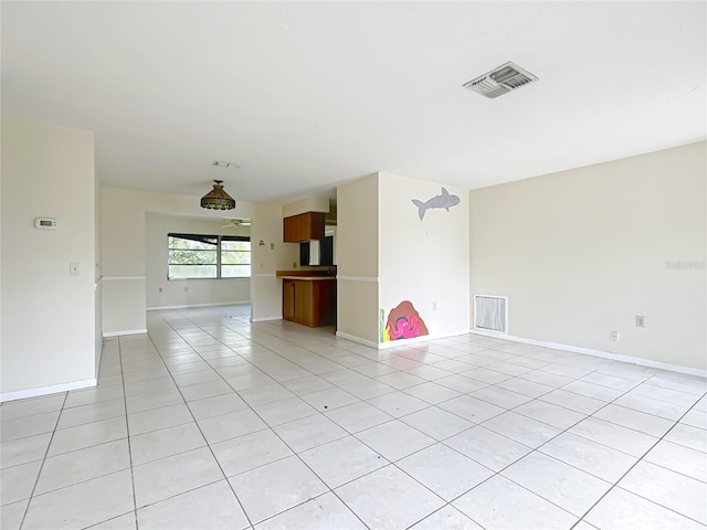 spare room featuring light tile patterned floors, visible vents, and baseboards