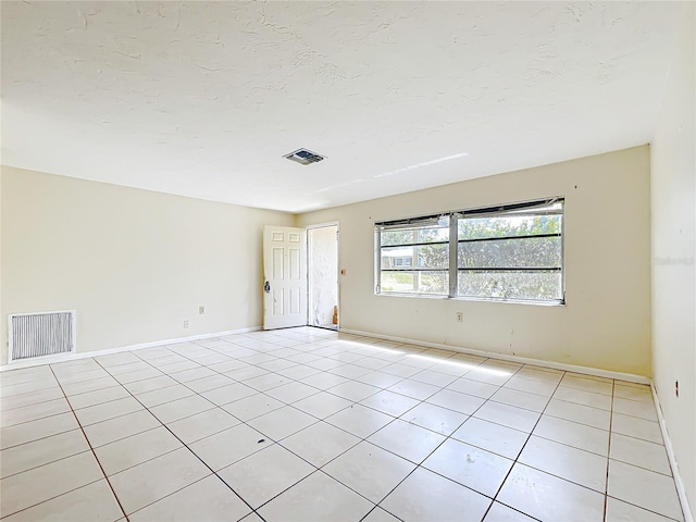 empty room with light tile patterned floors, visible vents, and a textured ceiling