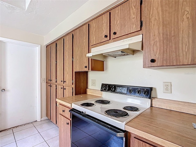 kitchen with light tile patterned floors, brown cabinetry, light countertops, under cabinet range hood, and white range with electric stovetop