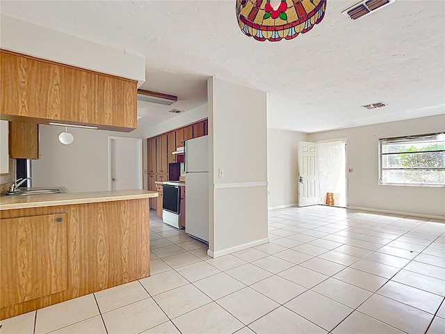 kitchen featuring visible vents, a sink, open floor plan, freestanding refrigerator, and light tile patterned flooring