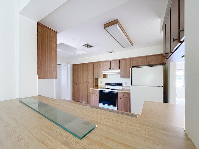 kitchen featuring visible vents, under cabinet range hood, white appliances, a peninsula, and light countertops