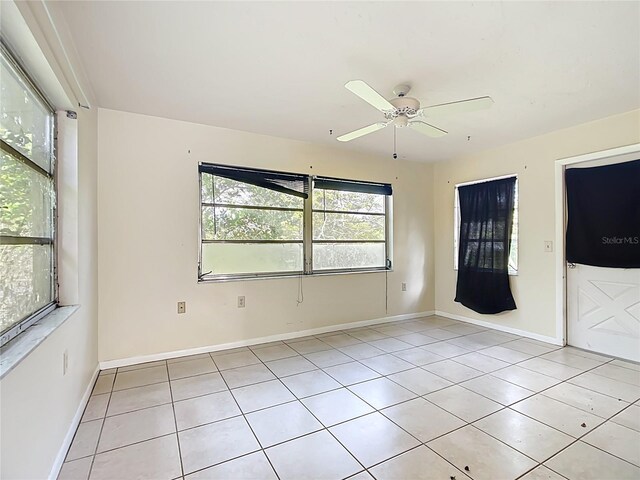 unfurnished room with light tile patterned floors, a ceiling fan, and baseboards