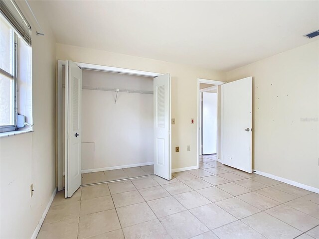 unfurnished bedroom featuring a closet, visible vents, baseboards, and light tile patterned floors