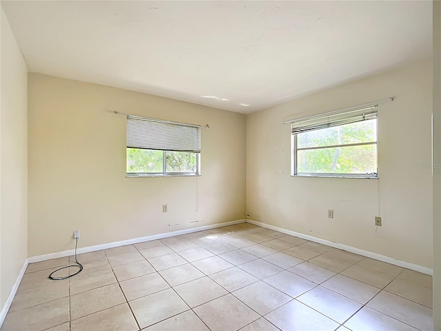 spare room featuring light tile patterned floors and baseboards