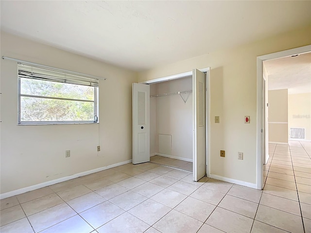 unfurnished bedroom featuring visible vents, light tile patterned flooring, baseboards, and a closet