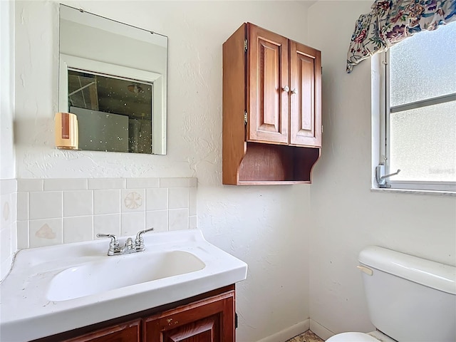 bathroom featuring vanity, toilet, and backsplash