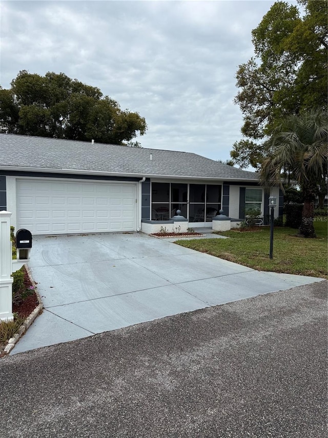 ranch-style house featuring a front lawn, roof with shingles, concrete driveway, an attached garage, and a sunroom