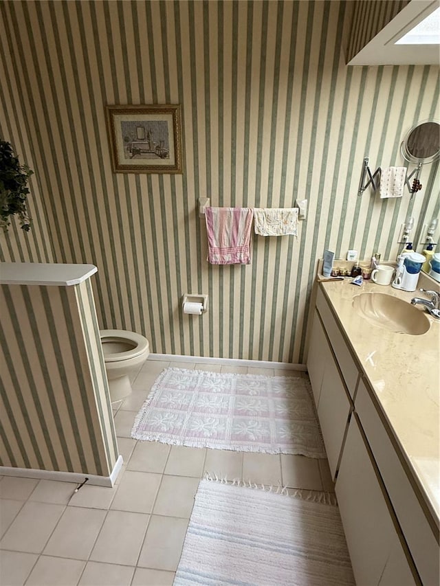 half bathroom featuring wallpapered walls, tile patterned floors, toilet, and vanity