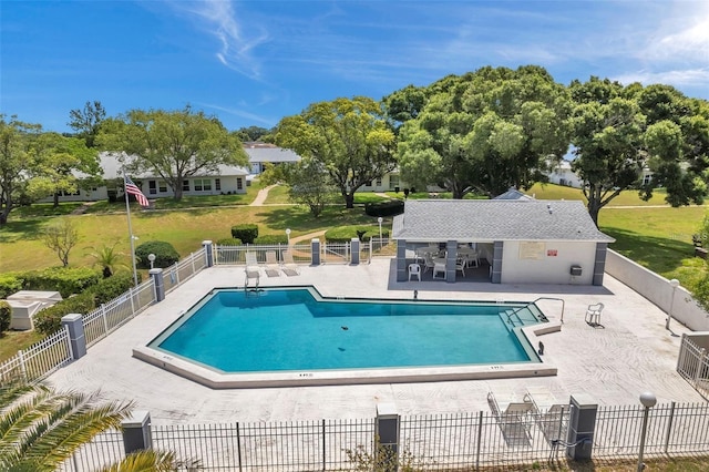 pool featuring a patio area, a yard, and fence