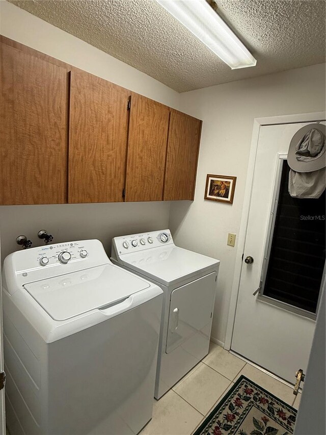 laundry room with cabinet space, a textured ceiling, independent washer and dryer, and light tile patterned flooring