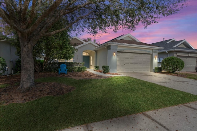 view of front of property with stucco siding, driveway, an attached garage, and a lawn