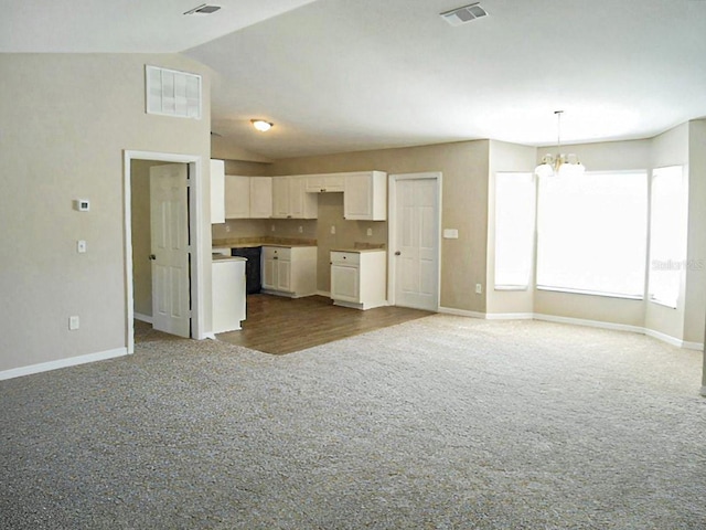 kitchen with visible vents, vaulted ceiling, carpet floors, a notable chandelier, and white cabinets