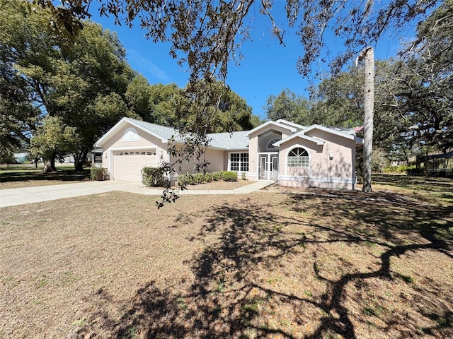 ranch-style home featuring stucco siding, concrete driveway, a garage, and a front yard