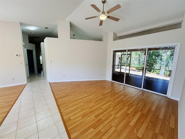 empty room with light wood finished floors, baseboards, ceiling fan, and vaulted ceiling