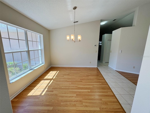 interior space featuring a textured ceiling, light wood-style floors, baseboards, a chandelier, and vaulted ceiling