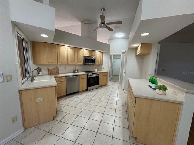 kitchen with a sink, stainless steel appliances, light brown cabinetry, and light tile patterned floors