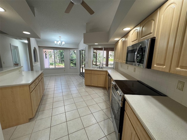 kitchen featuring light brown cabinets, backsplash, a textured ceiling, stainless steel appliances, and light tile patterned floors