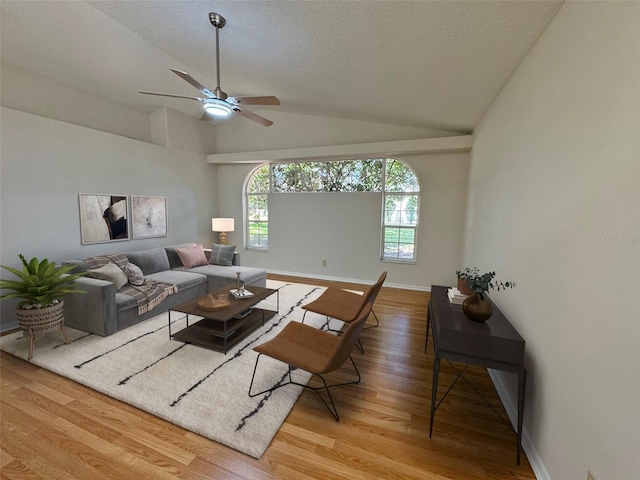 living area featuring baseboards, ceiling fan, lofted ceiling, wood finished floors, and a textured ceiling