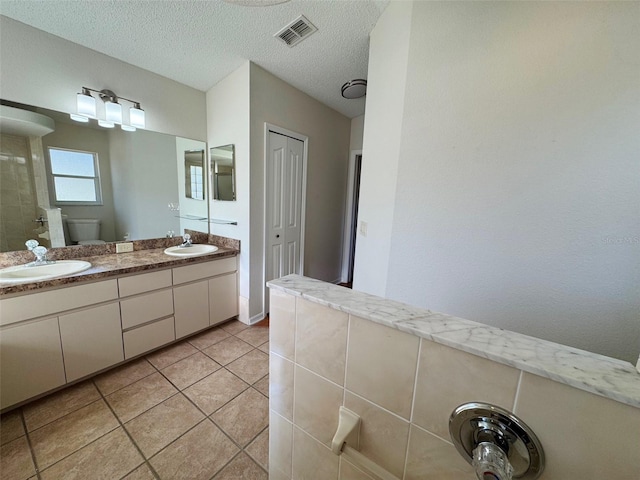 full bathroom featuring tile patterned floors, visible vents, toilet, a textured ceiling, and vanity